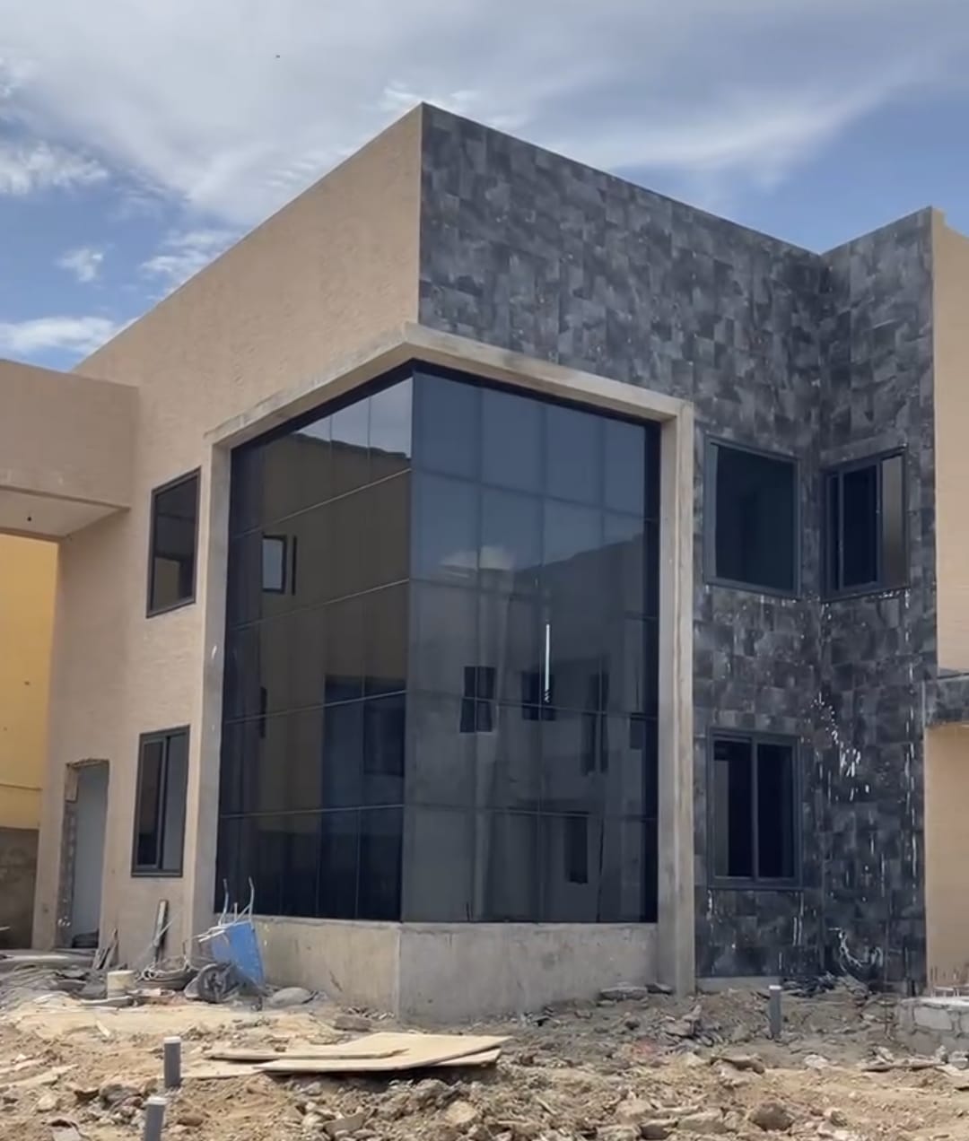 Prefabricated home under construction with full-height glass façade and stone cladding